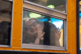 kid smiling through school bus window